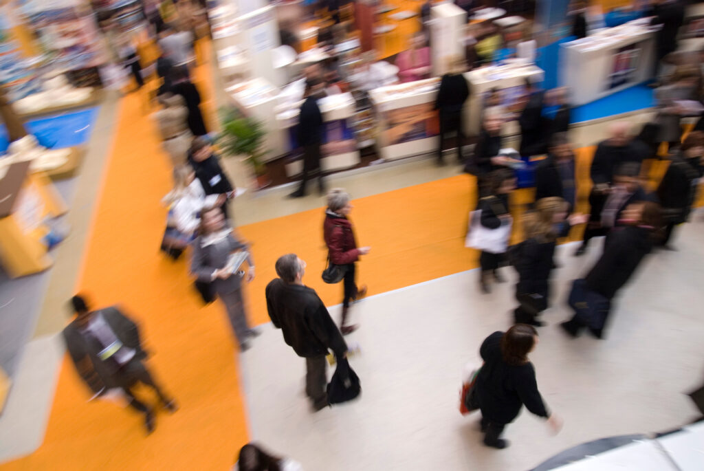 visiteurs passants dans les stands d'un salon d'exposants