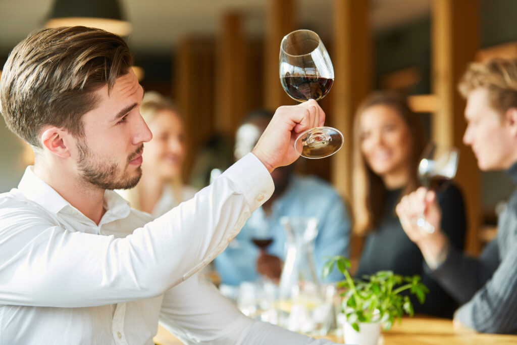 Dégustation Jeune homme avec un verre dans une dégustation regarde la qualité du vin rouge