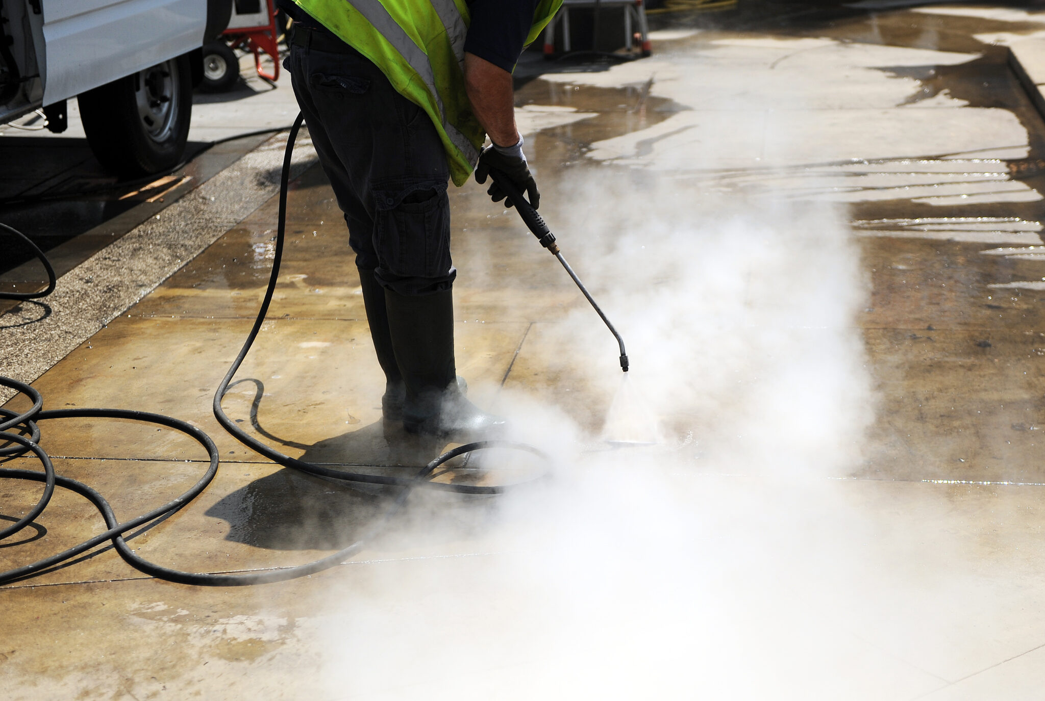 Hygiène Un homme nettoie le sol avec un jet d'eau à pression