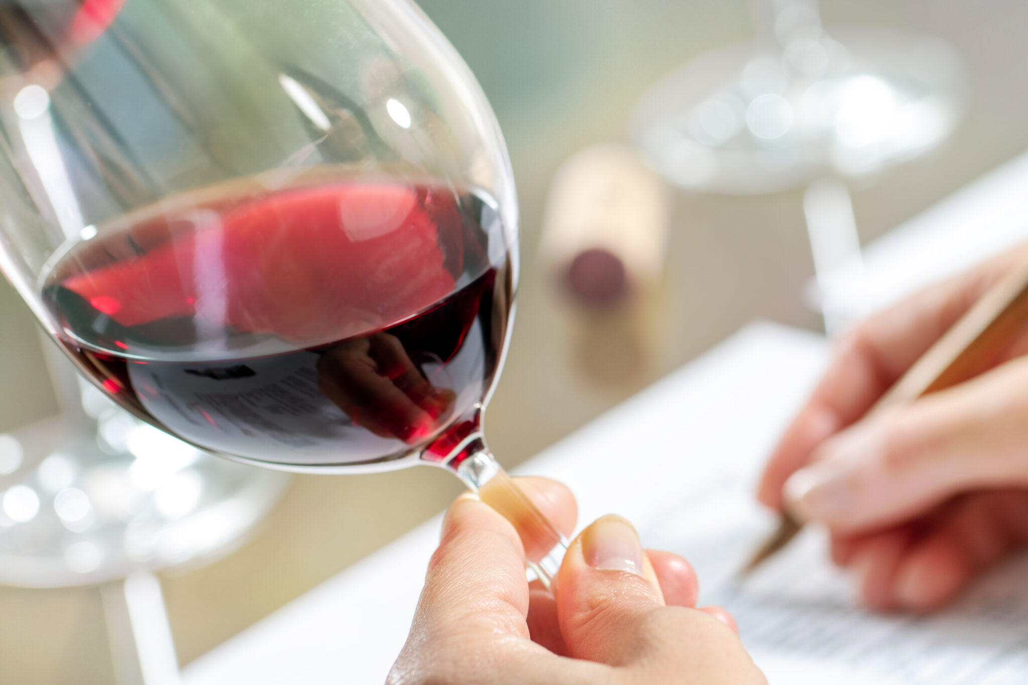 Dégustation Gros plan sur un verre de vin rouge avec une main prenant des notes sur une table